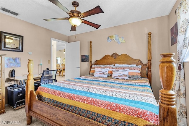 bedroom featuring light carpet, a textured ceiling, visible vents, and a ceiling fan