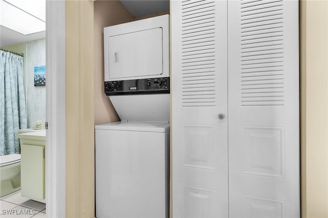 washroom with stacked washer / dryer, laundry area, and light tile patterned flooring