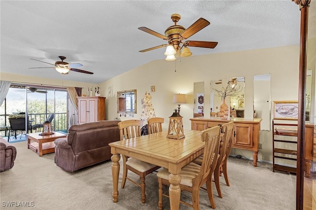 dining room with vaulted ceiling, ceiling fan, a textured ceiling, and light colored carpet