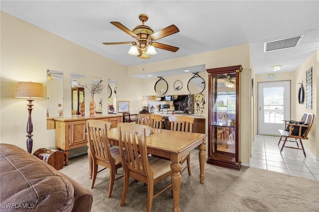 dining space with a ceiling fan, light colored carpet, visible vents, and light tile patterned floors