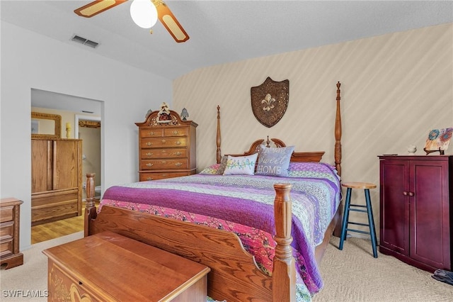 bedroom featuring light carpet, a ceiling fan, visible vents, and wallpapered walls