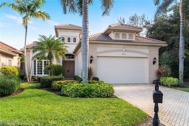 mediterranean / spanish home featuring a garage and a front lawn