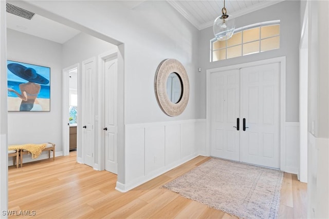 entryway featuring a notable chandelier, crown molding, and wood-type flooring