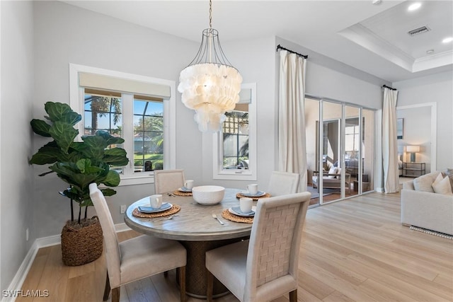 dining room featuring light hardwood / wood-style flooring, a raised ceiling, and a chandelier