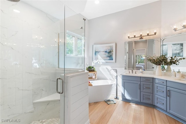 bathroom featuring independent shower and bath, a healthy amount of sunlight, hardwood / wood-style flooring, and vanity