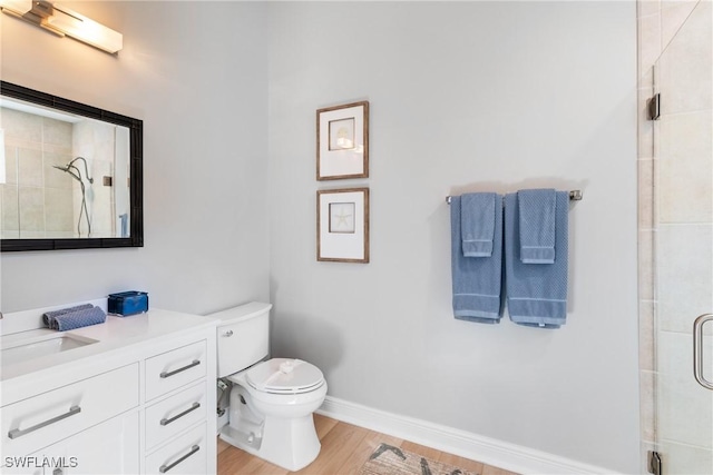 bathroom with vanity, hardwood / wood-style flooring, a shower with shower door, and toilet