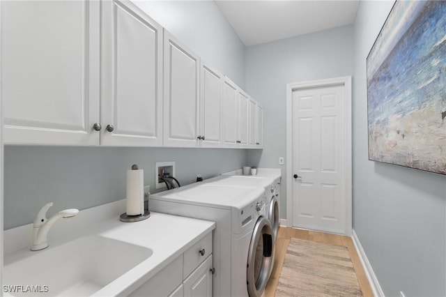 laundry area with cabinets, light hardwood / wood-style floors, sink, and washing machine and dryer