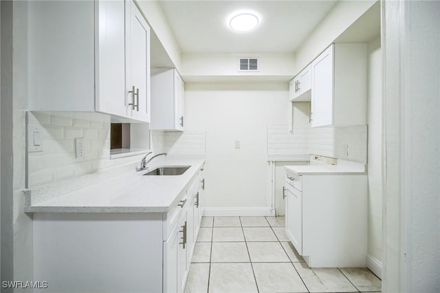 kitchen with white cabinetry, light tile patterned flooring, sink, and tasteful backsplash