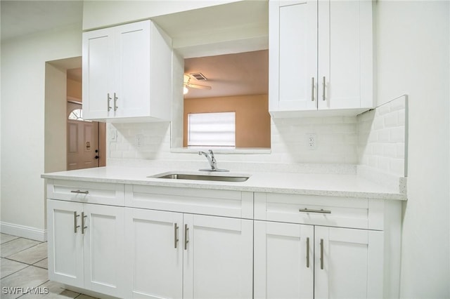 kitchen with tasteful backsplash, sink, light stone counters, and white cabinets