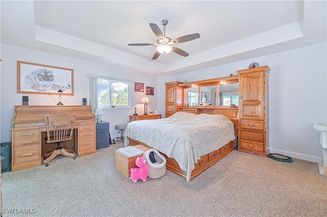 bedroom with ceiling fan, a tray ceiling, and light carpet