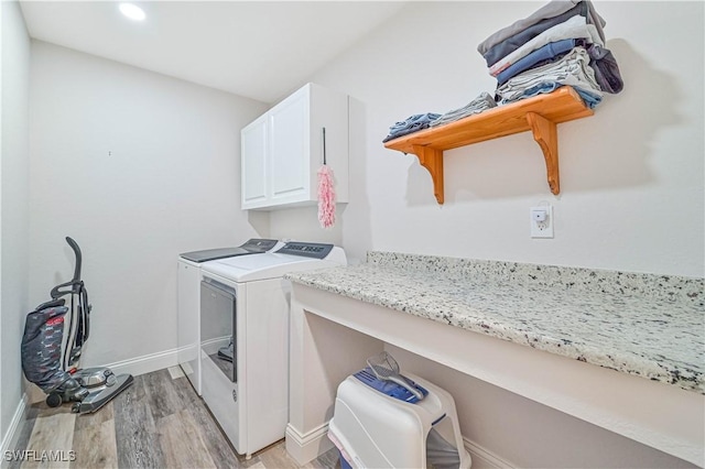 laundry room featuring cabinets, washing machine and clothes dryer, and light wood-type flooring