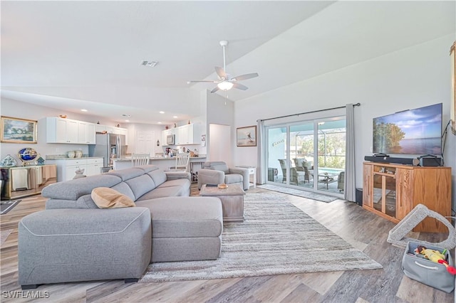 living room featuring ceiling fan, lofted ceiling, and light hardwood / wood-style flooring