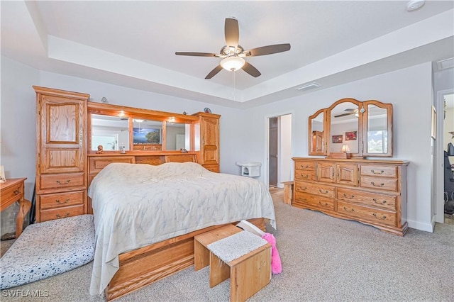 carpeted bedroom featuring ceiling fan and a tray ceiling