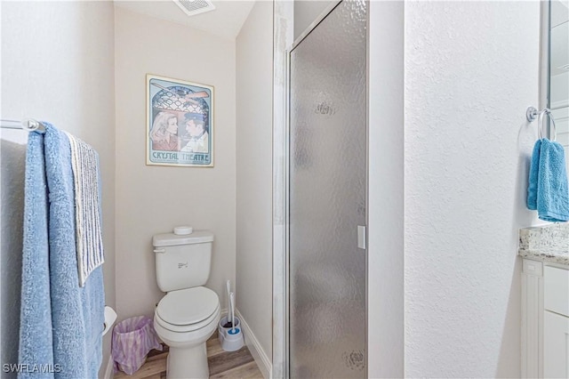 bathroom with hardwood / wood-style flooring, vanity, a shower with shower door, and toilet