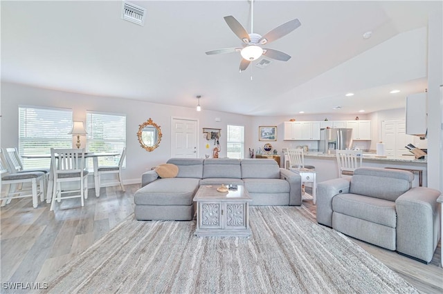 living room featuring ceiling fan, lofted ceiling, and light hardwood / wood-style flooring