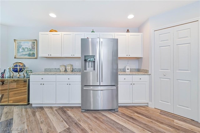 kitchen featuring light stone counters, stainless steel fridge with ice dispenser, and white cabinets