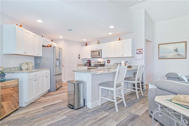 kitchen featuring light stone counters, stainless steel appliances, light wood-type flooring, and white cabinets