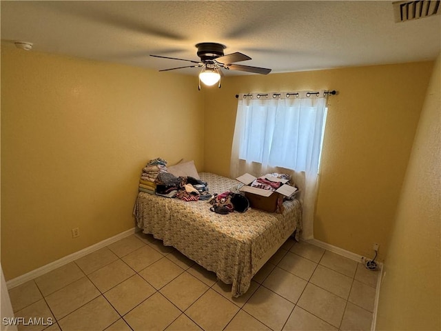 bedroom with ceiling fan, light tile patterned floors, and a textured ceiling