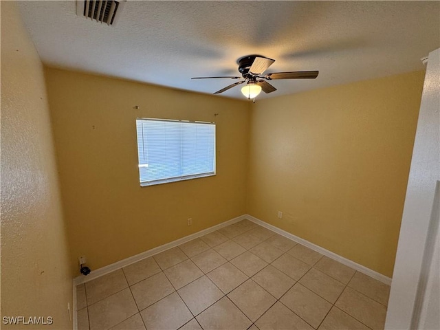 tiled empty room featuring ceiling fan and a textured ceiling