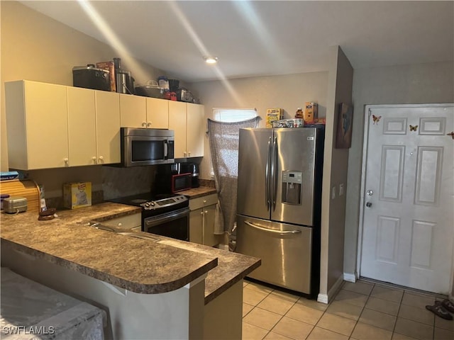 kitchen with light tile patterned floors, stainless steel appliances, and kitchen peninsula