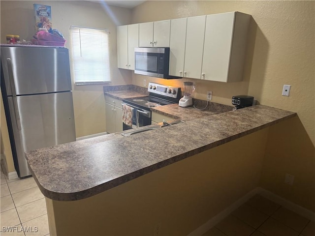 kitchen featuring appliances with stainless steel finishes, sink, light tile patterned flooring, kitchen peninsula, and white cabinets