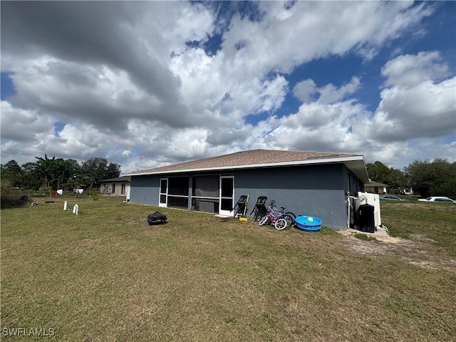 rear view of property featuring a lawn and a sunroom