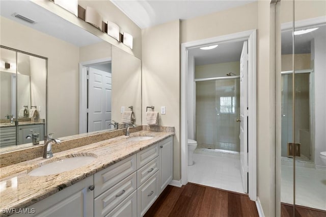 bathroom featuring vanity, toilet, a shower with shower door, and hardwood / wood-style floors