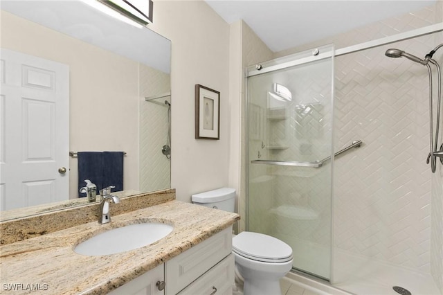 bathroom featuring vanity, toilet, and a shower with door