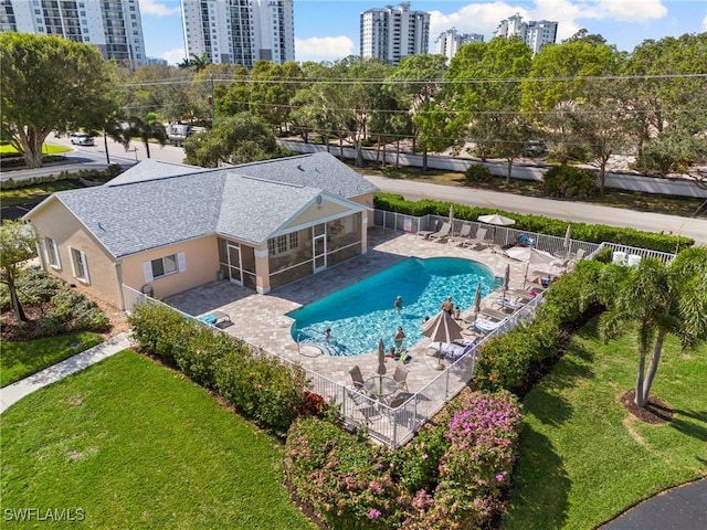 view of swimming pool featuring a sunroom, a patio, and a lawn