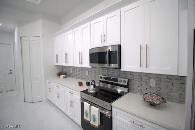 kitchen with stainless steel appliances, white cabinets, and backsplash