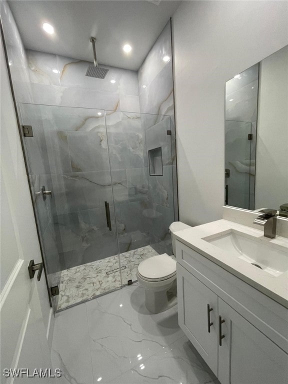 bathroom featuring a shower with door, vanity, and toilet