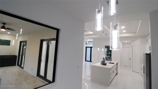 hallway featuring a raised ceiling and sink