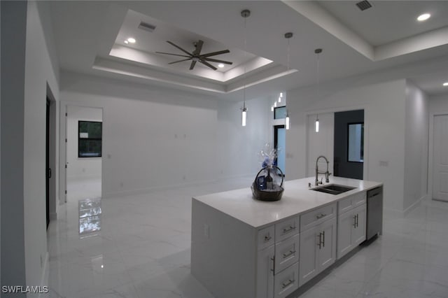 kitchen with stainless steel dishwasher, a raised ceiling, sink, and a center island with sink