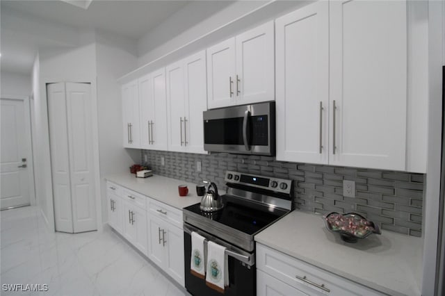 kitchen featuring decorative backsplash, white cabinets, and appliances with stainless steel finishes