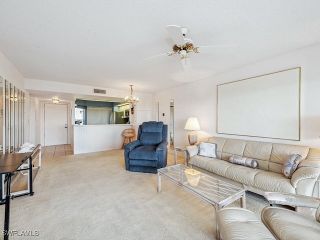 carpeted living room with ceiling fan with notable chandelier