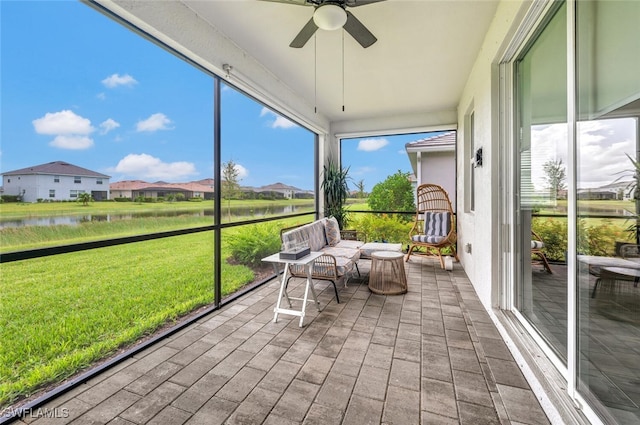 unfurnished sunroom featuring ceiling fan and a water view