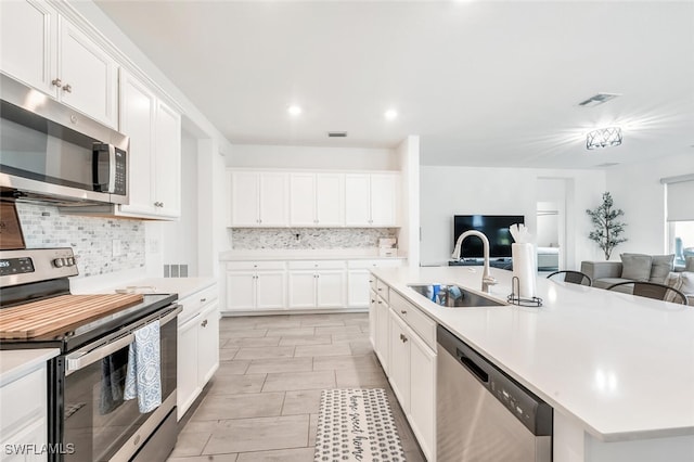 kitchen with white cabinetry, an island with sink, stainless steel appliances, and sink