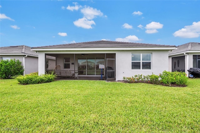 rear view of property featuring a yard and a sunroom