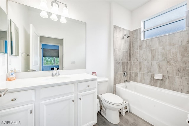 full bathroom featuring tiled shower / bath, vanity, and toilet