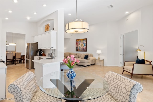 dining area with sink, a towering ceiling, and light tile patterned flooring