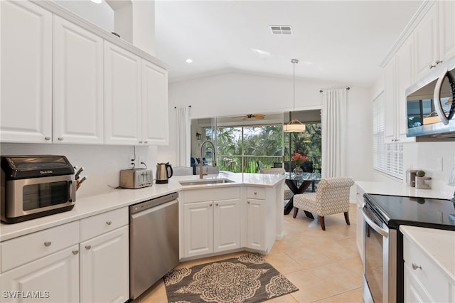 kitchen with sink, light tile patterned floors, appliances with stainless steel finishes, hanging light fixtures, and white cabinets