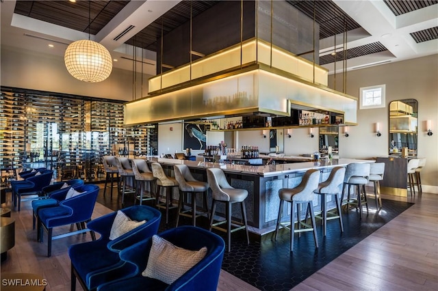 kitchen with pendant lighting, dark hardwood / wood-style flooring, coffered ceiling, and a high ceiling