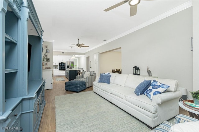 living room with crown molding, ceiling fan, and light wood-type flooring