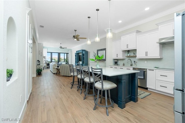 kitchen featuring white cabinetry, a kitchen island, decorative light fixtures, and appliances with stainless steel finishes