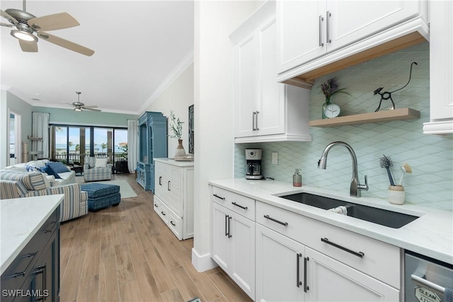 kitchen featuring light stone countertops, sink, dishwasher, and white cabinets