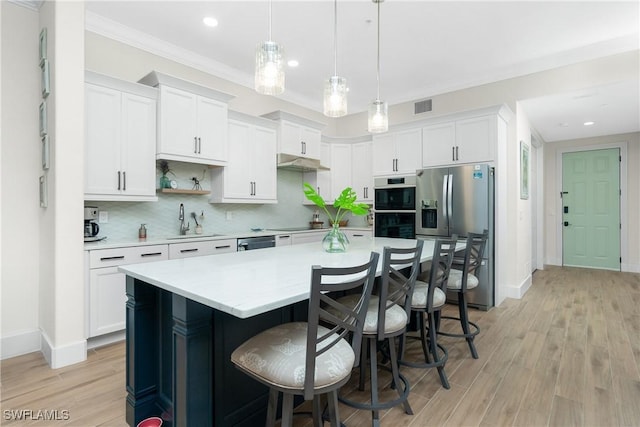 kitchen featuring pendant lighting, stainless steel appliances, a center island, and white cabinets