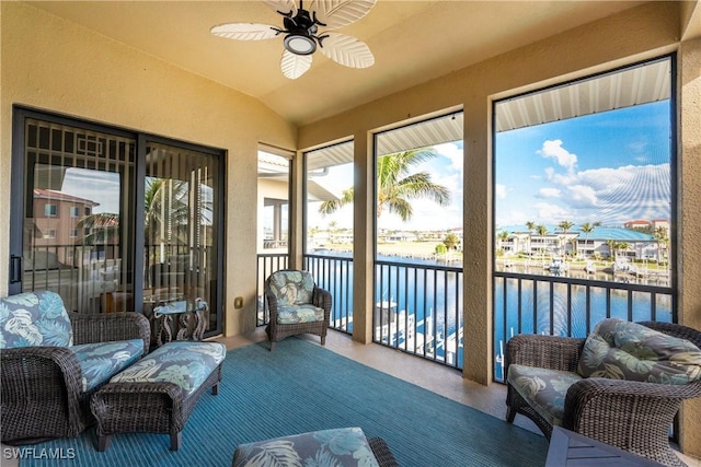 sunroom / solarium with lofted ceiling, ceiling fan, and a water view