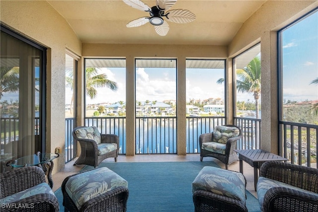 sunroom featuring ceiling fan, a healthy amount of sunlight, and a water view