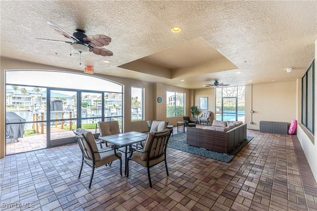 dining area featuring a tray ceiling, ceiling fan, and a water view