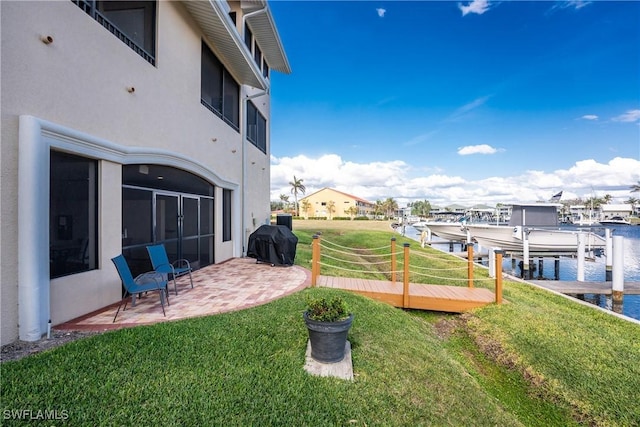 view of yard featuring a patio, a boat dock, and a water view